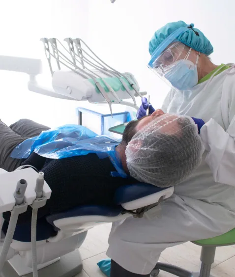Dentista realizando tratamiento a paciente con equipación de protección completa